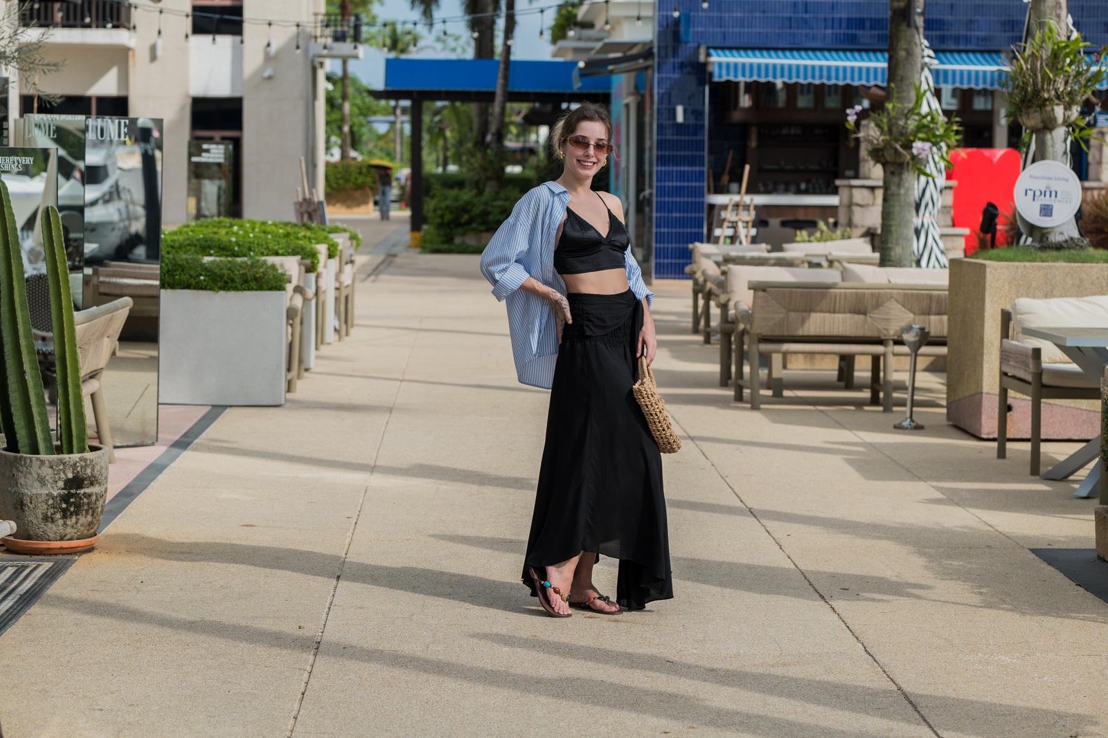 Woman wearing a black skirt and blue overshirt in a sunny outdoor courtyard